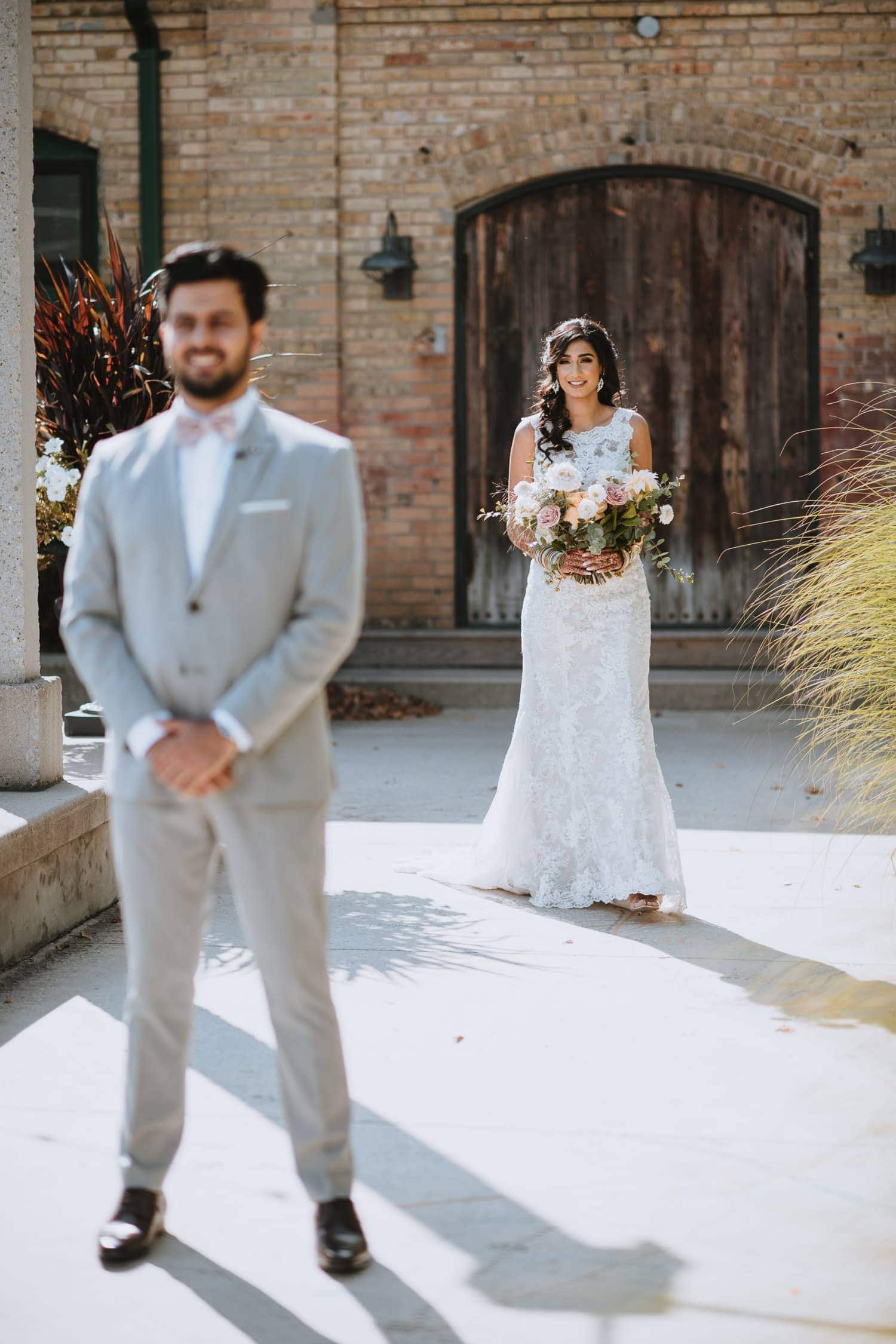 Bride approaching groom for their first look at the Hacienda Sarria patio in Kitchener, Ontario