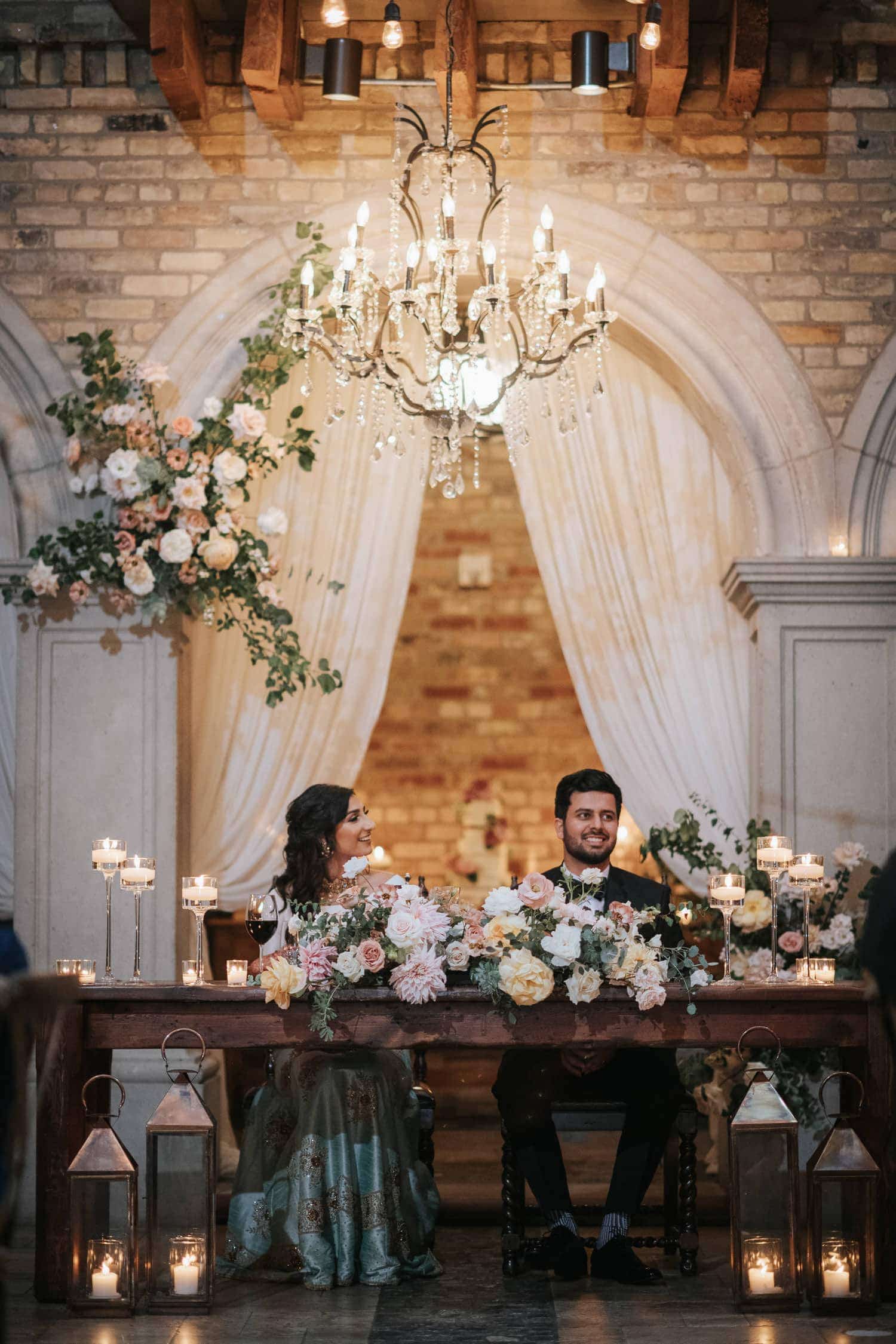 Bride and groom sitting at the head table during wedding reception in Hacienda Sarria