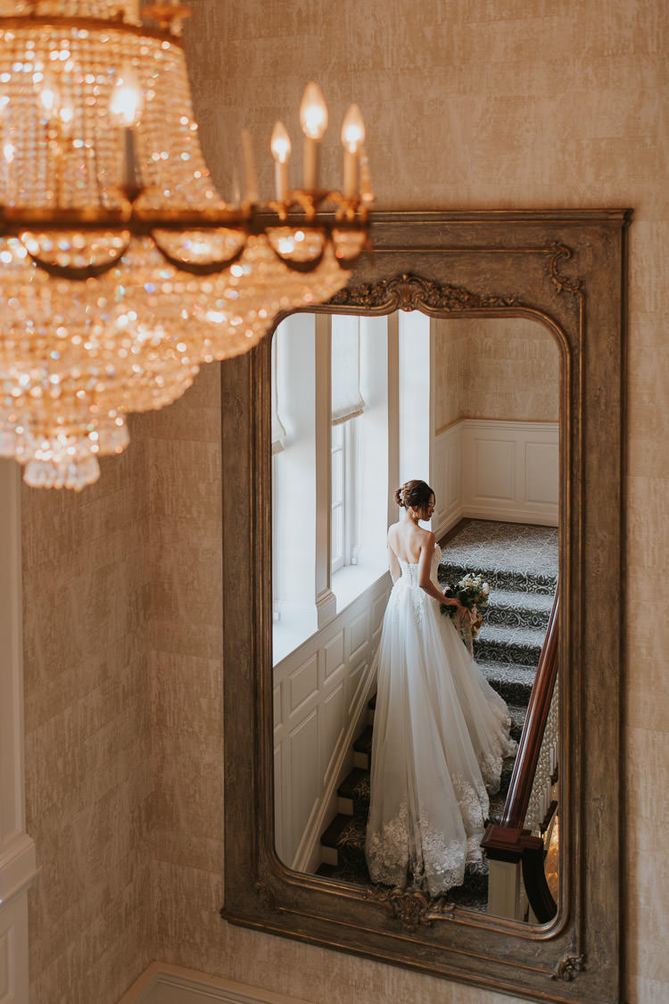 An elegant bride with her wedding gown draping down at the stairs inside Graydon Hall Manor in toronto