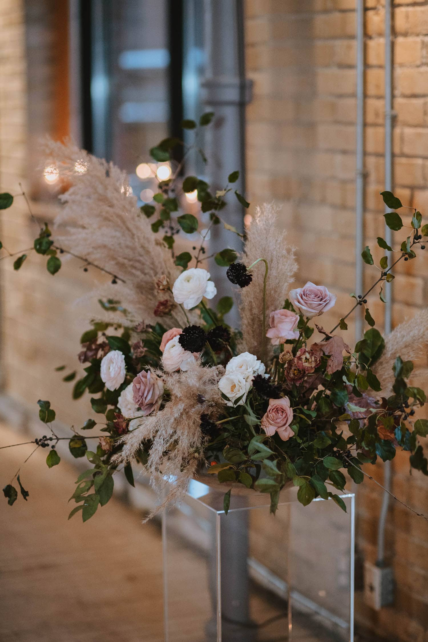 wedding ceremony centerpiece with dusty pinks, whites, pops of burgundy, and soft, fluffy pampas grass.