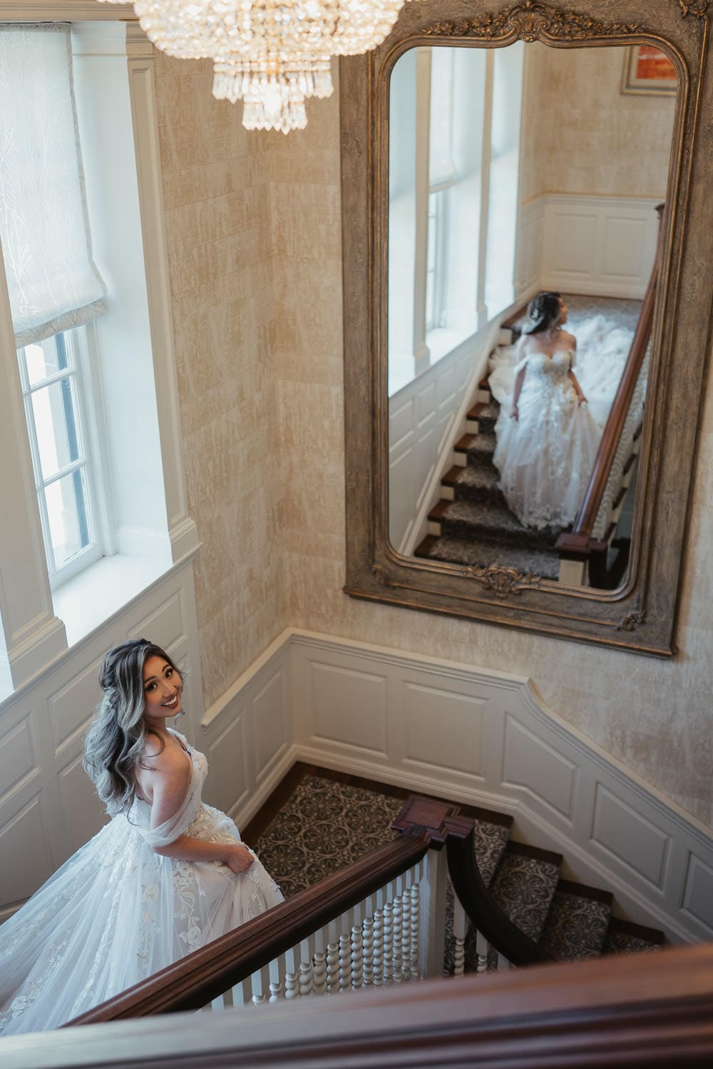 Portrait of bride walking down the stairscase decorated with a chandelier inside the Graydon Hall Manor