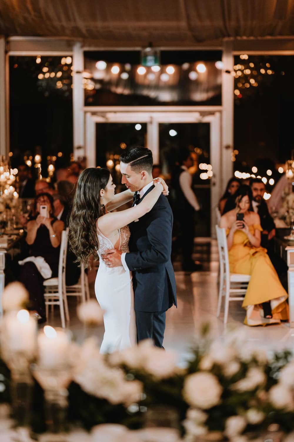 first dance of bride and groom inside the glass pavilion